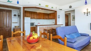 A dining area with a wooden table, chairs, and a bowl of fruit.