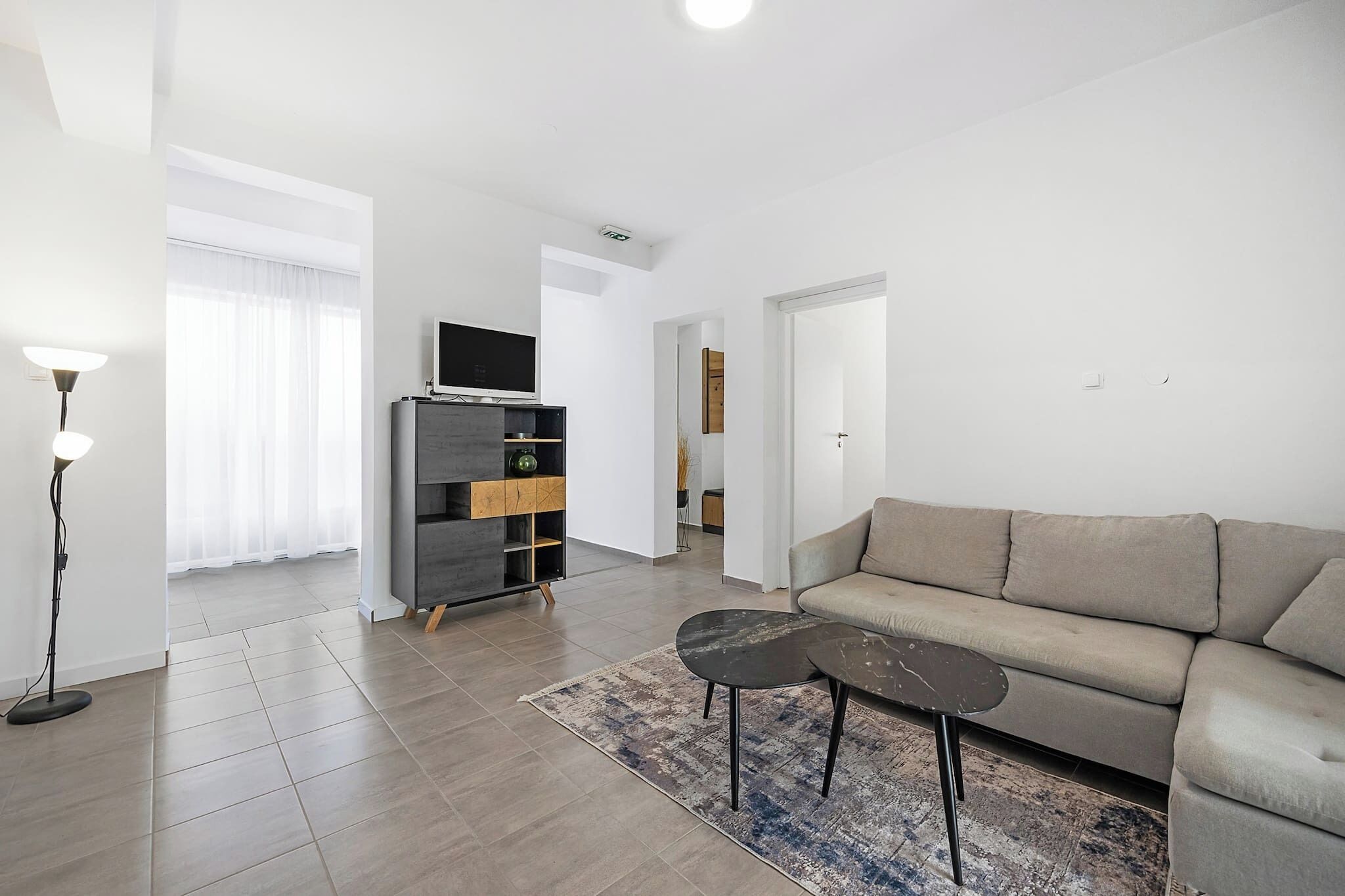 A modern living room with a sofa, a coffee table, and a TV on a stand.