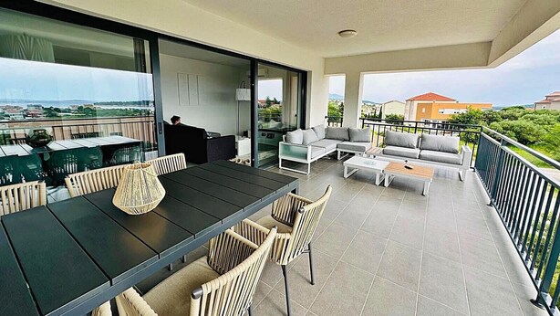 Un grand balcon doté d’un espace repas, de sièges et offrant une vue sur le paysage urbain.