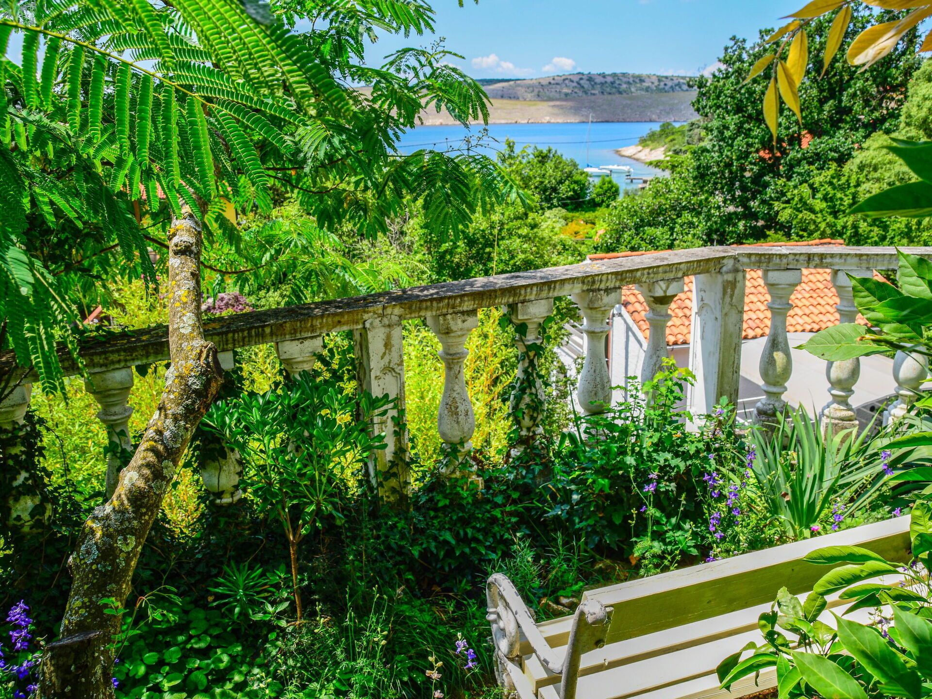 A lush garden with a stone balustrade overlooking a body of water.