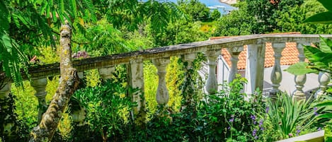 A lush garden with a stone balustrade overlooking a body of water.