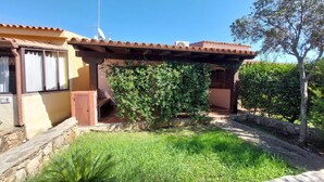 Une maison avec un toit en tuiles, une véranda et un jardin bien entretenu.