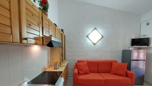 Une cuisine compacte avec des meubles en bois, un lave-linge encastré et un canapé rouge.