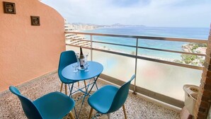 Ein Balkon mit Tisch und Stühlen mit Blick auf die Küste.