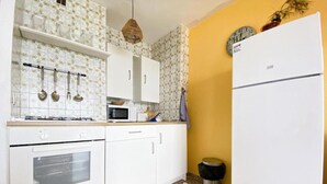 Eine kleine Küche mit weißen Schränken, einer Mikrowelle, einem Herd und einem Kühlschrank.