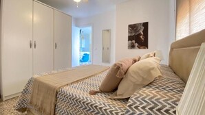 Ein Schlafzimmer mit Bett, Deckenventilator, Kleiderschrank und einer Tür zu einem Badezimmer.
