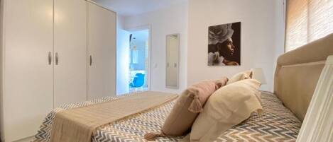 Een slaapkamer met een bed, een plafondventilator, een kledingkast en een deur naar een badkamer.