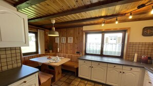 A kitchen with wooden cabinets, a tiled floor, and a window with a view of the outside.