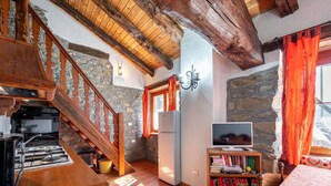 A rustic interior with a wooden staircase, stone walls, a kitchen area, a television, and a bookshelf. - Lovely apartment for 4 people with WIFI, TV and pets allowed (Avise)