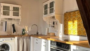 Une cuisine compacte équipée d’un lave-linge, d’une cuisinière et de placards.