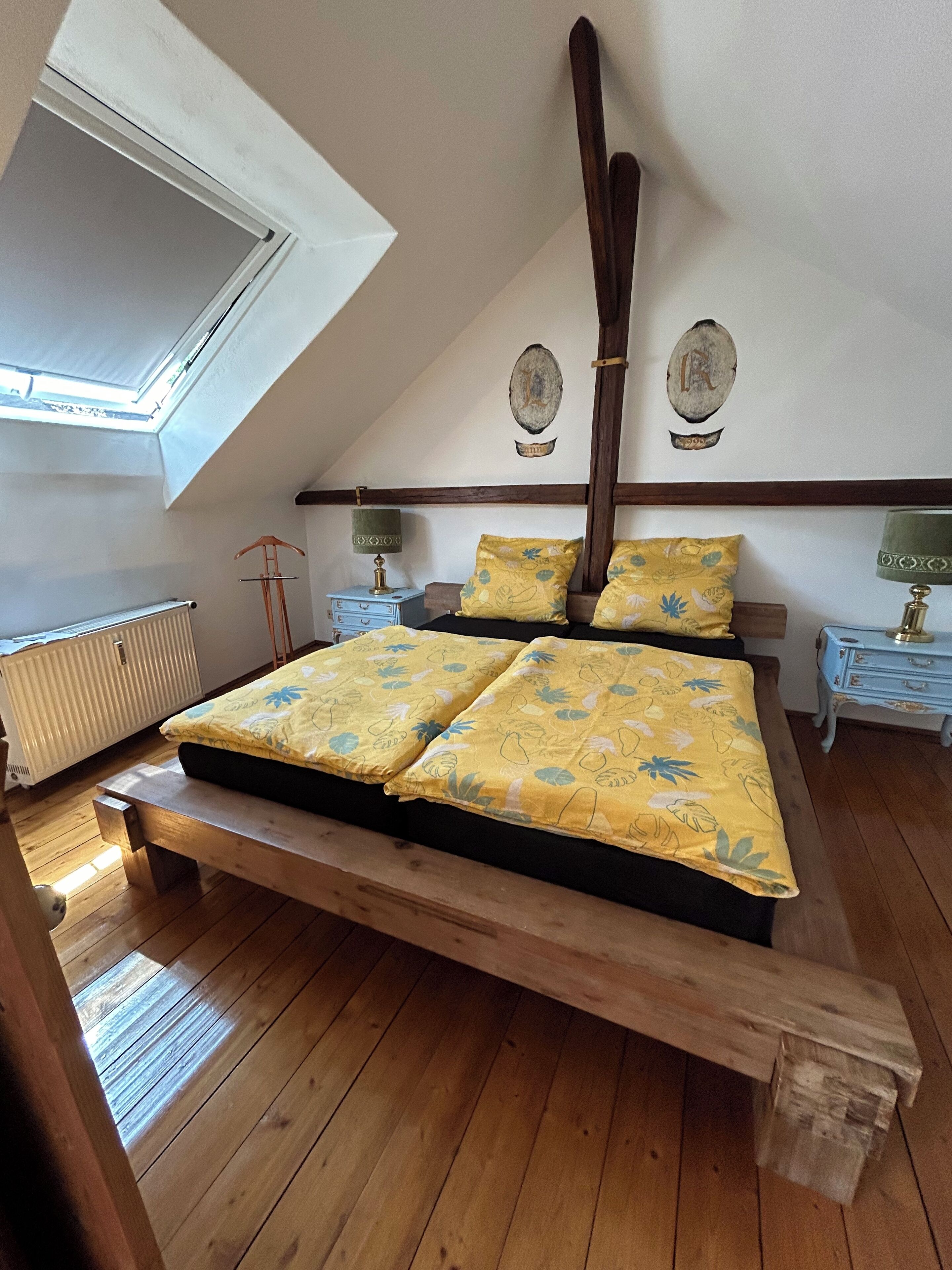 Ein Schlafzimmer mit einem Holzbett, einem Oberlicht, einer Heizung und zwei Nachttischen mit Lampen.