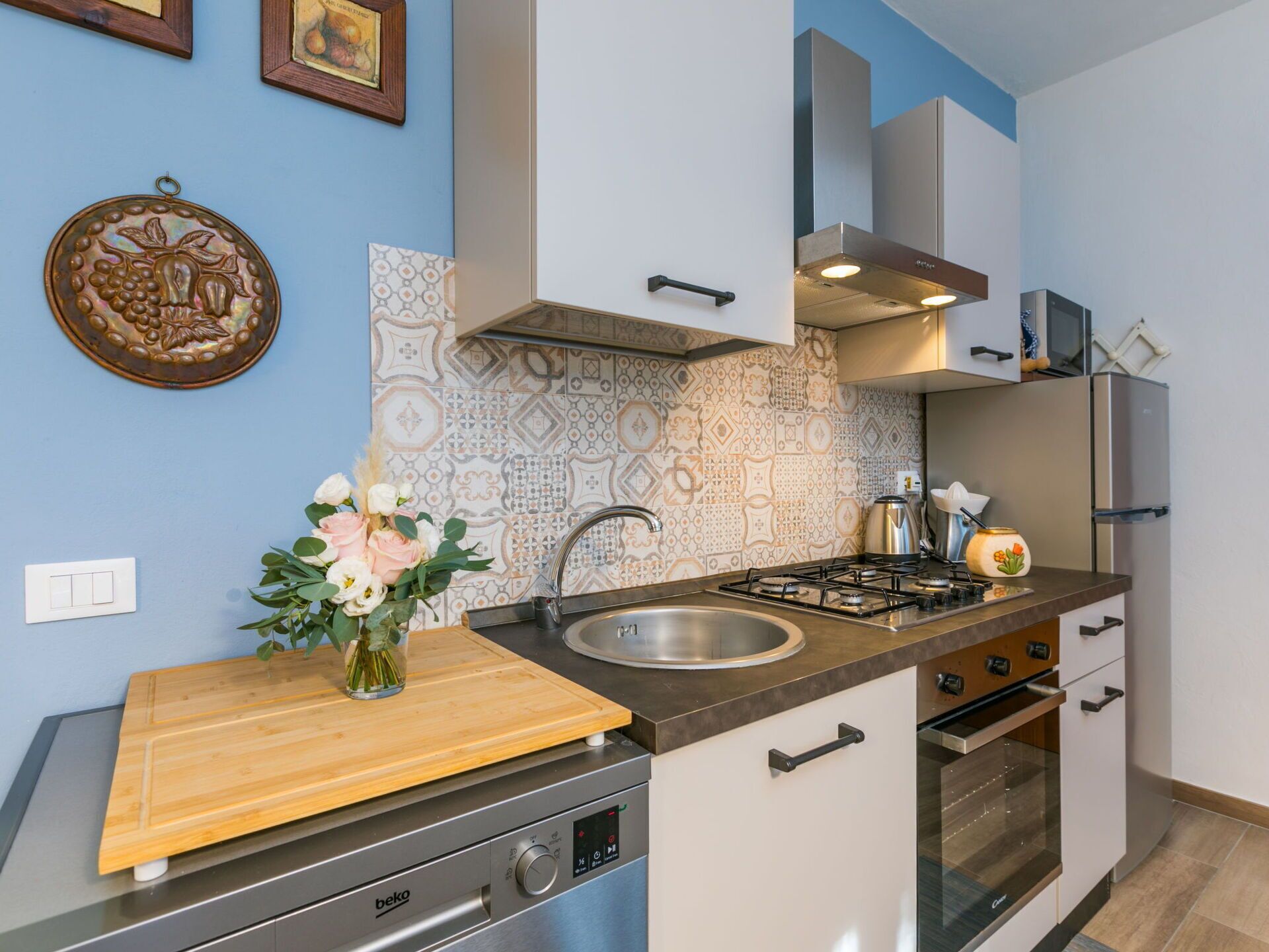 A modern kitchen with a gas stove, stainless steel appliances, and patterned backsplash.