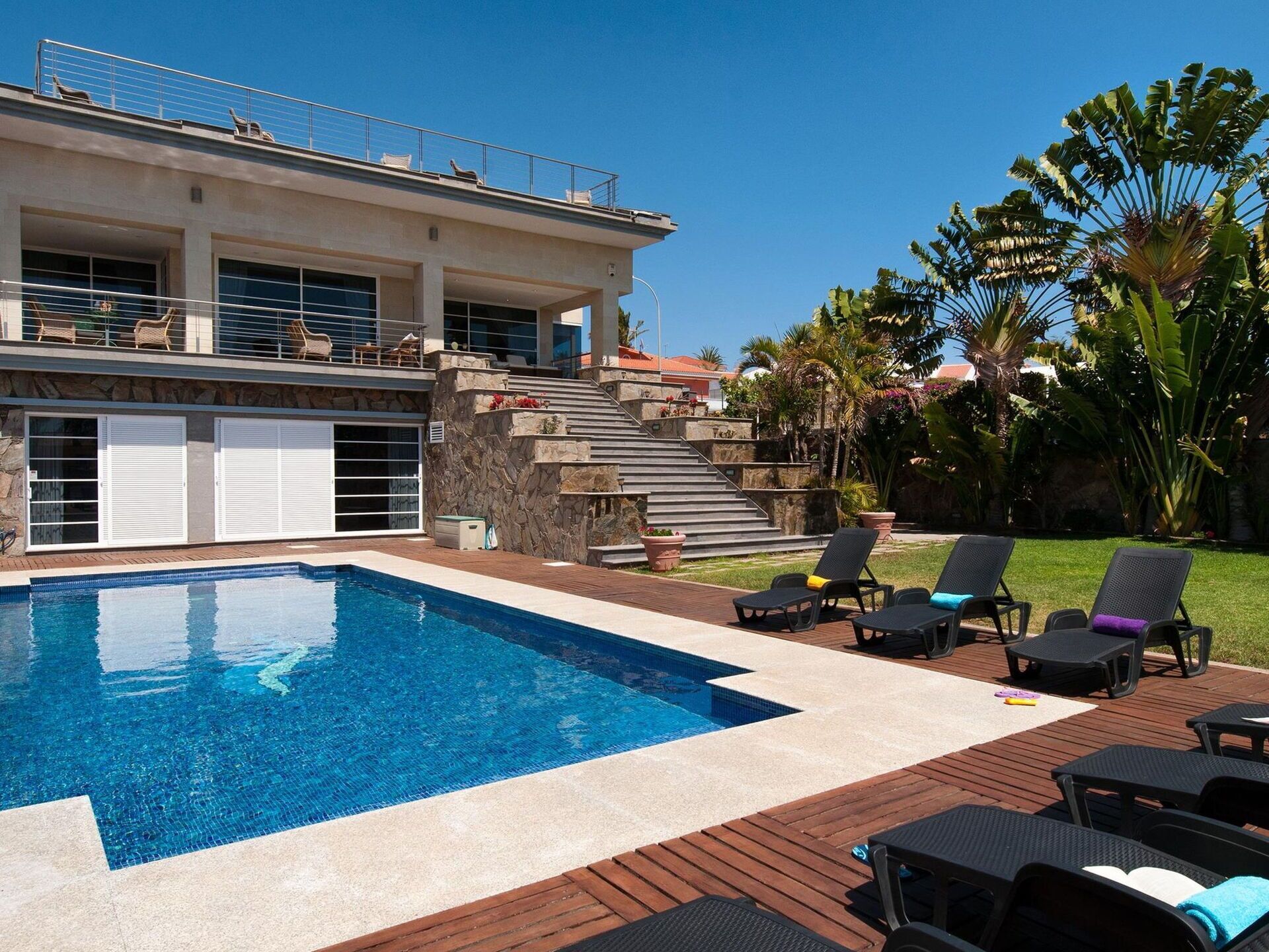 Uma casa moderna com piscina, área de estar ao ar livre e escadaria de pedra.