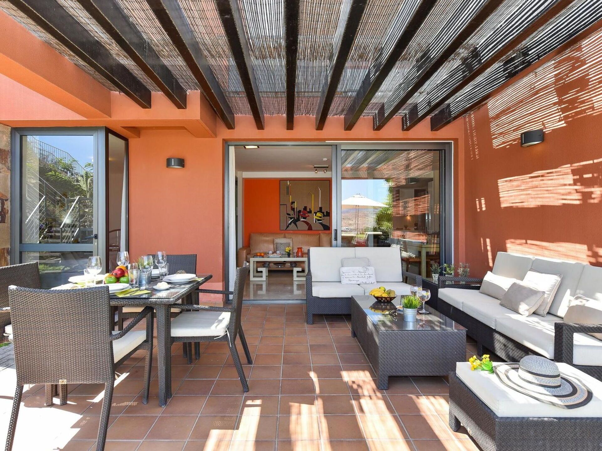 An outdoor patio with a dining area, seating, and a view of the interior.