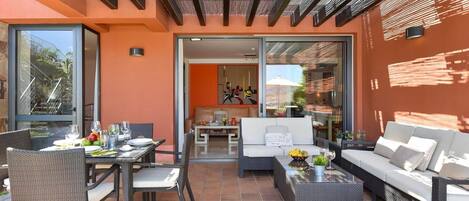 An outdoor patio with a dining area, seating, and a view of the interior.