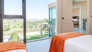 Une chambre d’hôtel dotée d’une grande porte-fenêtre coulissante donnant sur un balcon avec vue sur un terrain de golf.