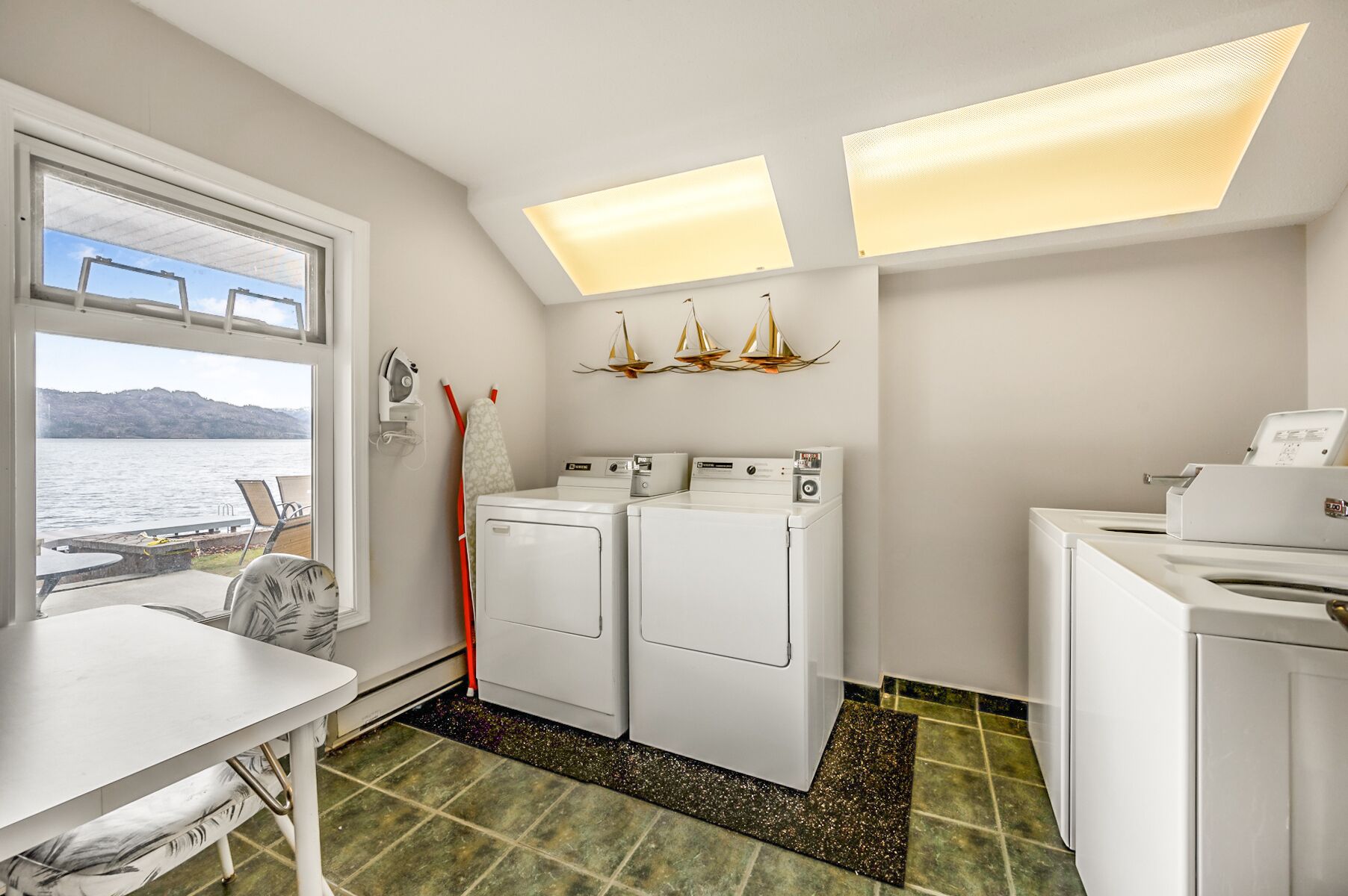 A laundry room with two washing machines, a drying rack, and a table with chairs.