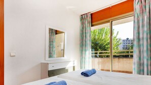 A hotel room with two beds, a large window with curtains, a mirror, and a small desk. - Nice apartment for 4 people with pool, WIFI, TV and patio (Salou)