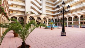 A multi-level courtyard with a central fountain, potted plants, and a tiled floor. - Beautiful apartment for 4 people with pool, WIFI, A/C, TV and patio (Salou)