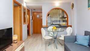 A compact living space with a TV, dining table, and sofa. - Beautiful apartment for 4 people with pool, WIFI, A/C, TV and patio (Salou)