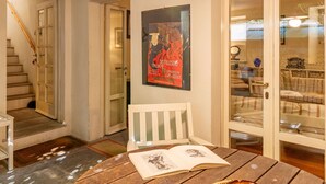 Une pièce chaleureuse avec une table en bois, une chaise, une affiche au mur et un escalier menant à une autre pièce.