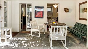 Une pièce avec un plafond en bois, des murs blancs, une table ronde entourée de chaises, un banc et un tableau encadré accroché au mur.