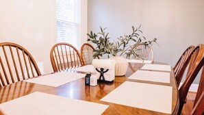 A dining table with six wooden chairs, a vase with green foliage, and two salt and pepper shakers on the table. - Beautiful Spacious 4 BR Retreat in Uptown with Fire Pit & Porch (Martinsville)