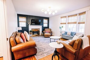 Ein Wohnzimmer mit Kamin, Ledersofas, einem Couchtisch und einem Fernseher.