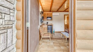 Un intérieur chaleureux avec un mur en pierre, un plafond en bois et un coin cuisine comprenant un évier, une cuisinière et des placards.