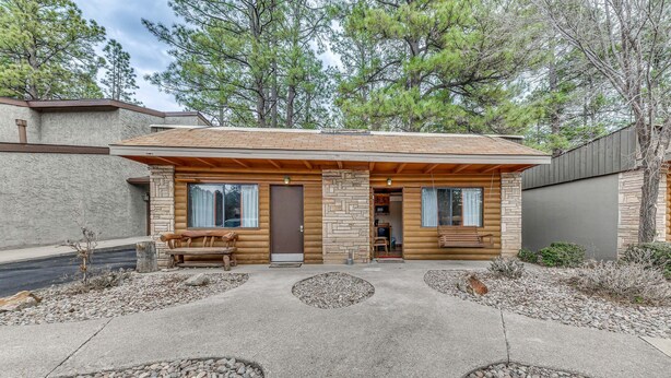 Une cabane en rondins avec une façade en pierre, un revêtement extérieur en bois et un porche à l’avant.