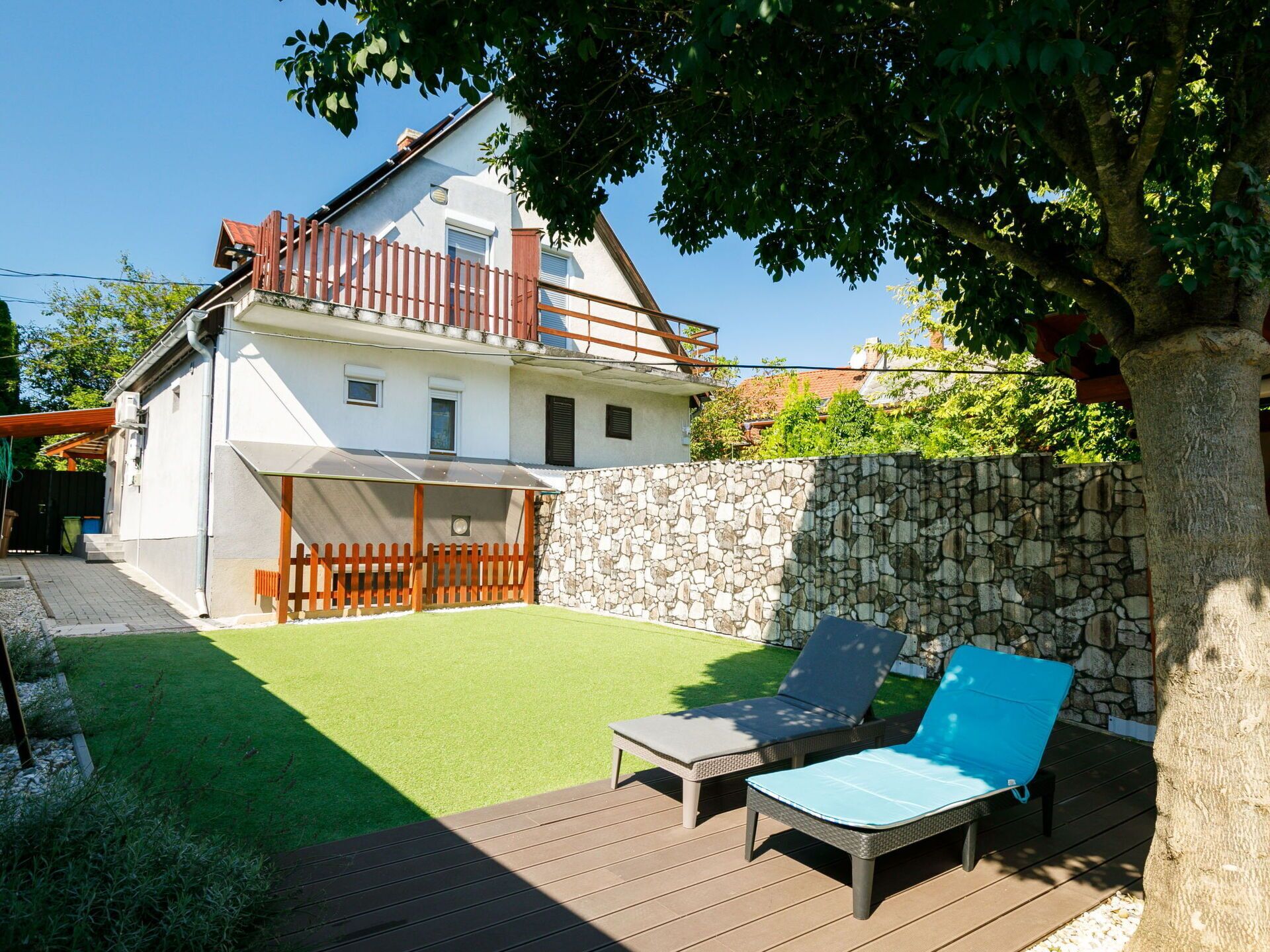 A two-story house with a stone wall and a wooden deck.