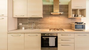 Une cuisine moderne avec des meubles de couleur bois clair, un évier en acier inoxydable, une cuisinière à gaz, un four à micro-ondes et un four encastré.