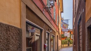Une ruelle étroite pavée, bordée d’immeubles, dont certains arborent des enseignes bien visibles.