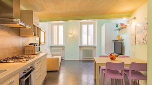Une cuisine moderne équipée d’une cuisinière à gaz, d’un four et d’un coin repas avec des chaises roses et une table.