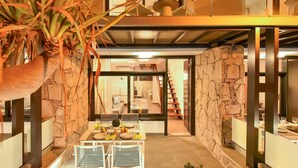 Un intérieur moderne comprenant un coin repas, des murs en pierre et un escalier menant à un autre niveau.