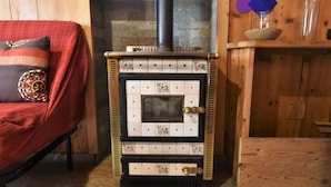A wood-burning stove with a tiled front, a chimney, and a wooden shelf above it. - Nice apartment for 4 people with WIFI, TV and pets allowed (Tartano)