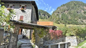 A stone building with a wooden balcony, stone steps, and a mountainous backdrop. - Nice apartment for 4 people with WIFI, TV and pets allowed (Tartano)