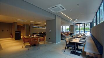A spacious indoor dining area with high ceilings, modern lighting, and large windows offering natural light.
