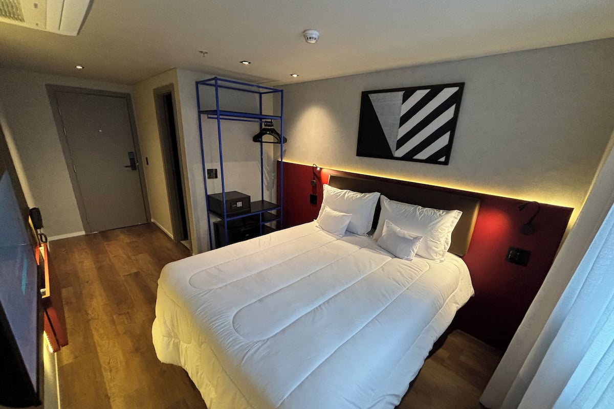 Une chambre d’hôtel avec un grand lit, une armoire, un bureau et une œuvre d’art accrochée au mur.