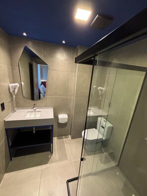Een moderne badkamer met een douchecabine van glas, een wastafelmeubel met een wastafel en een toilet.