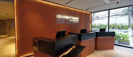A reception desk with a sign reading "GOLDENTOWER" and a modern interior design.