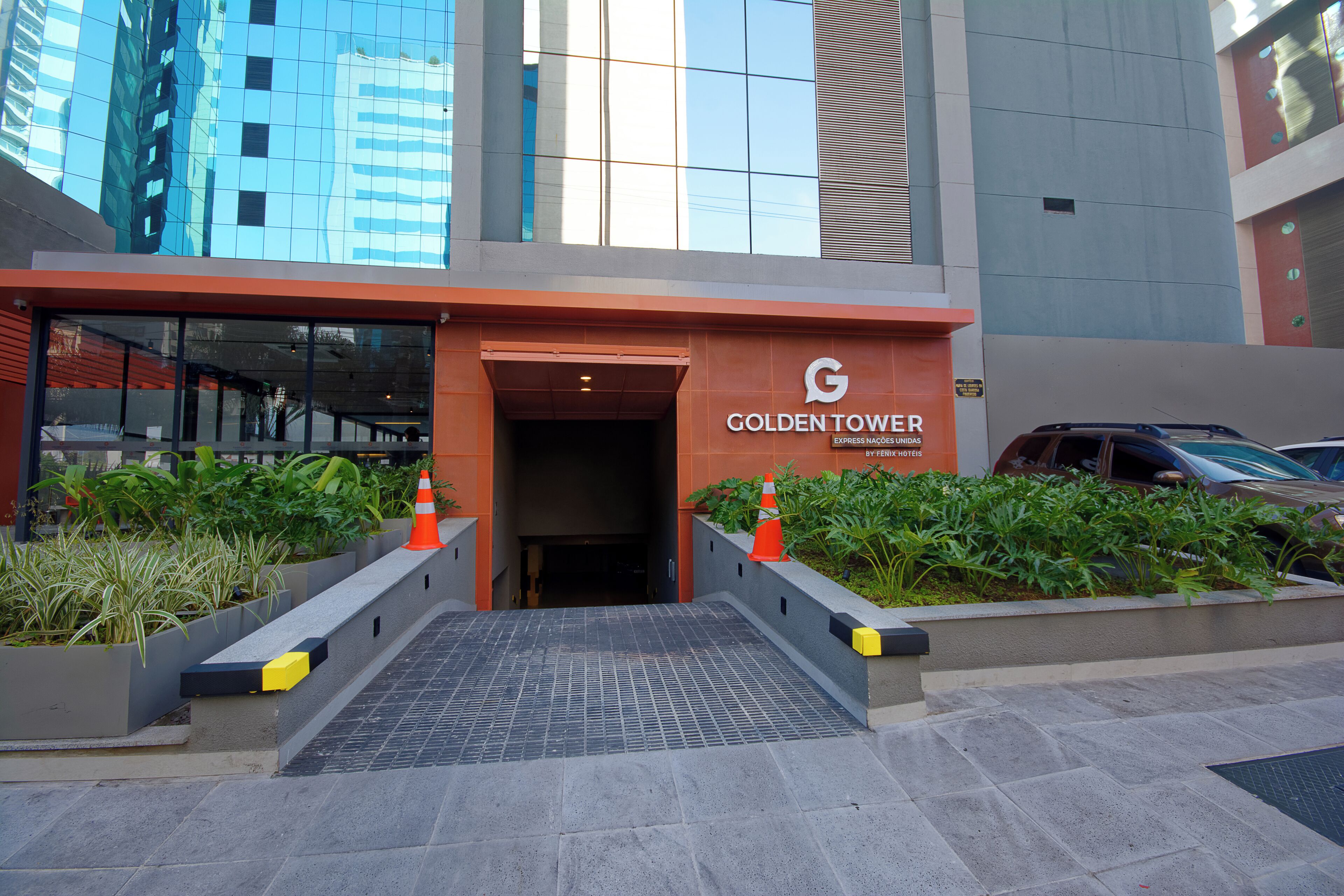 The entrance to the Golden Tower hotel with a modern design, featuring a glass facade and a ramp leading to the entrance.