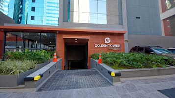 The entrance to the Golden Tower hotel with a modern design, featuring a glass facade and a ramp leading to the entrance.
