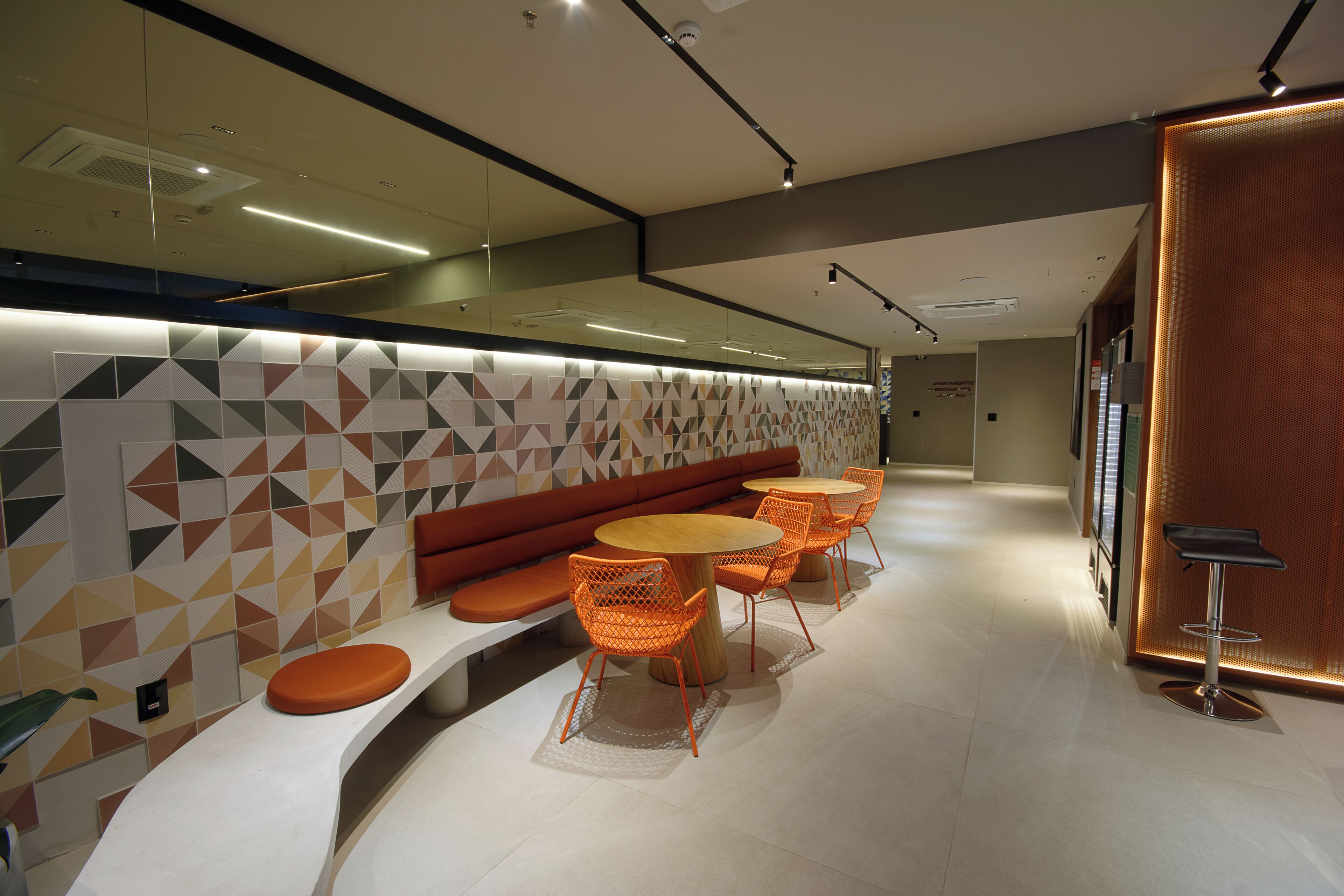 Ein modernes Interieur mit einer gebogenen Bank, orangefarbenen Stühlen und runden Tischen.