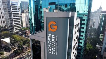 Un edificio de gran altura con un llamativo logo en forma de 'G' y el nombre 'Golden Tower Express Nações Unidas'.