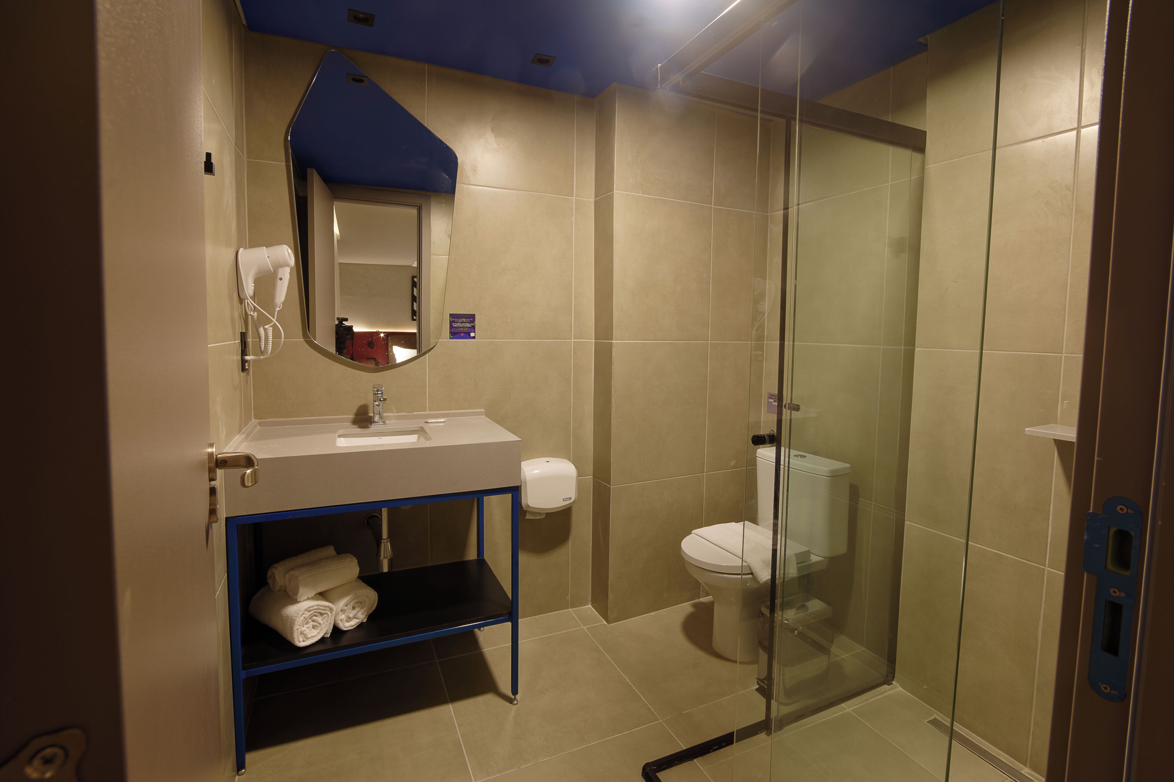 A bathroom with a glass shower enclosure, a sink with a mirror, and a towel rack.