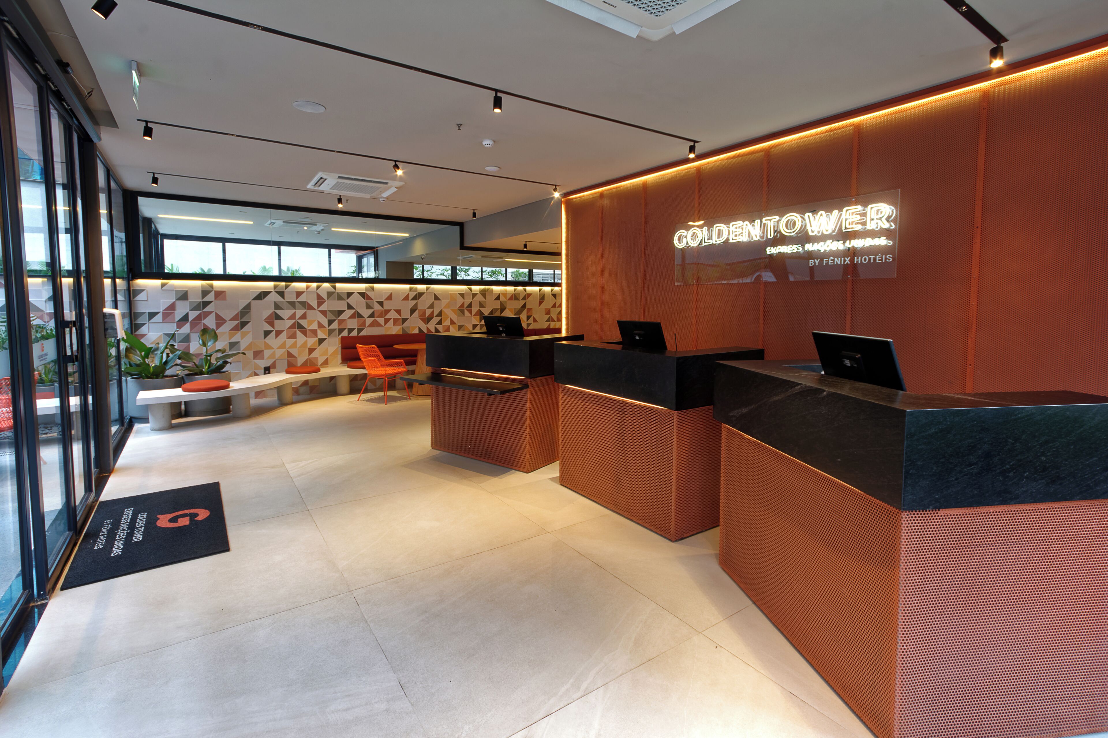 Zona d'entrada d'un hotel amb un disseny modern, que inclou una taulell de recepció, zona de seients i un gran finestral amb vista a l'exterior.