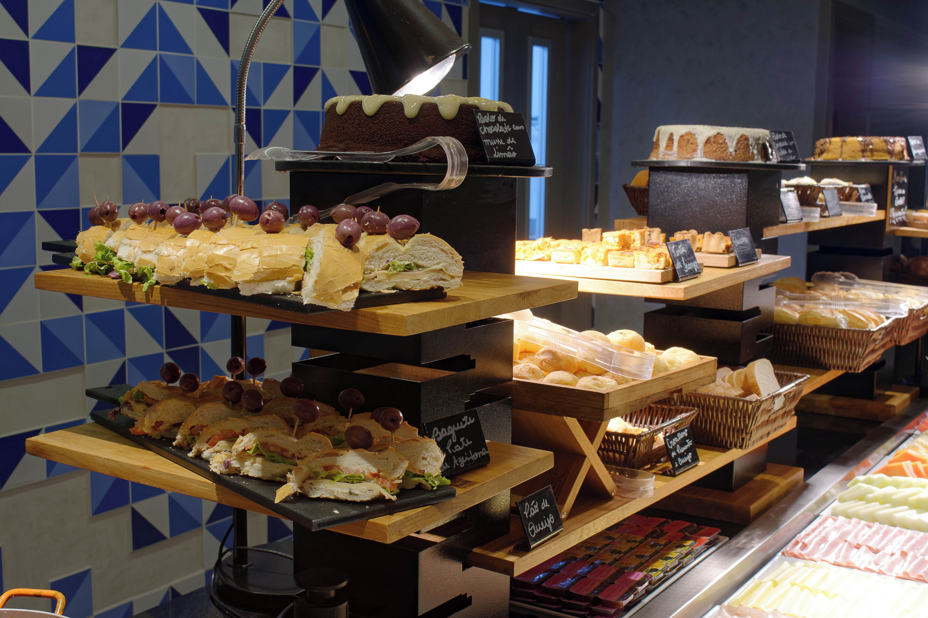 Una vitrina de panadería con diversos pasteles y sándwiches.