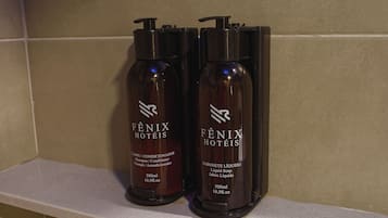 Two bottles of Fenix Hotels shampoo and conditioner on a shelf.