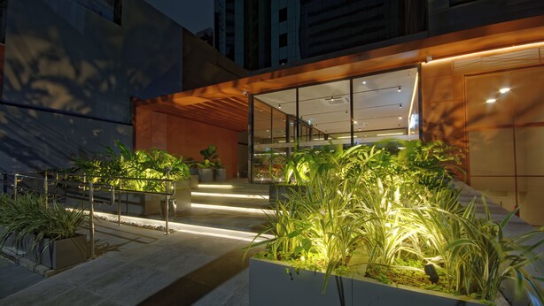 A modern building with a glass entrance, outdoor lighting, and potted plants. - Golden Tower Express Nações Unidas by Fênix Hotéis (São Paulo)